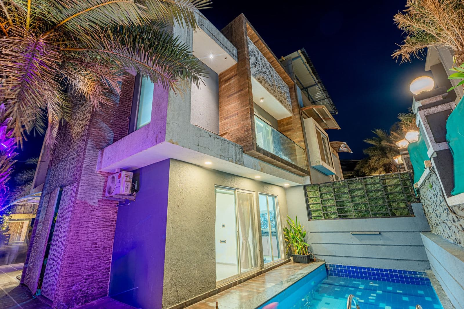 Villa exterior at night with pool and purple accent lighting