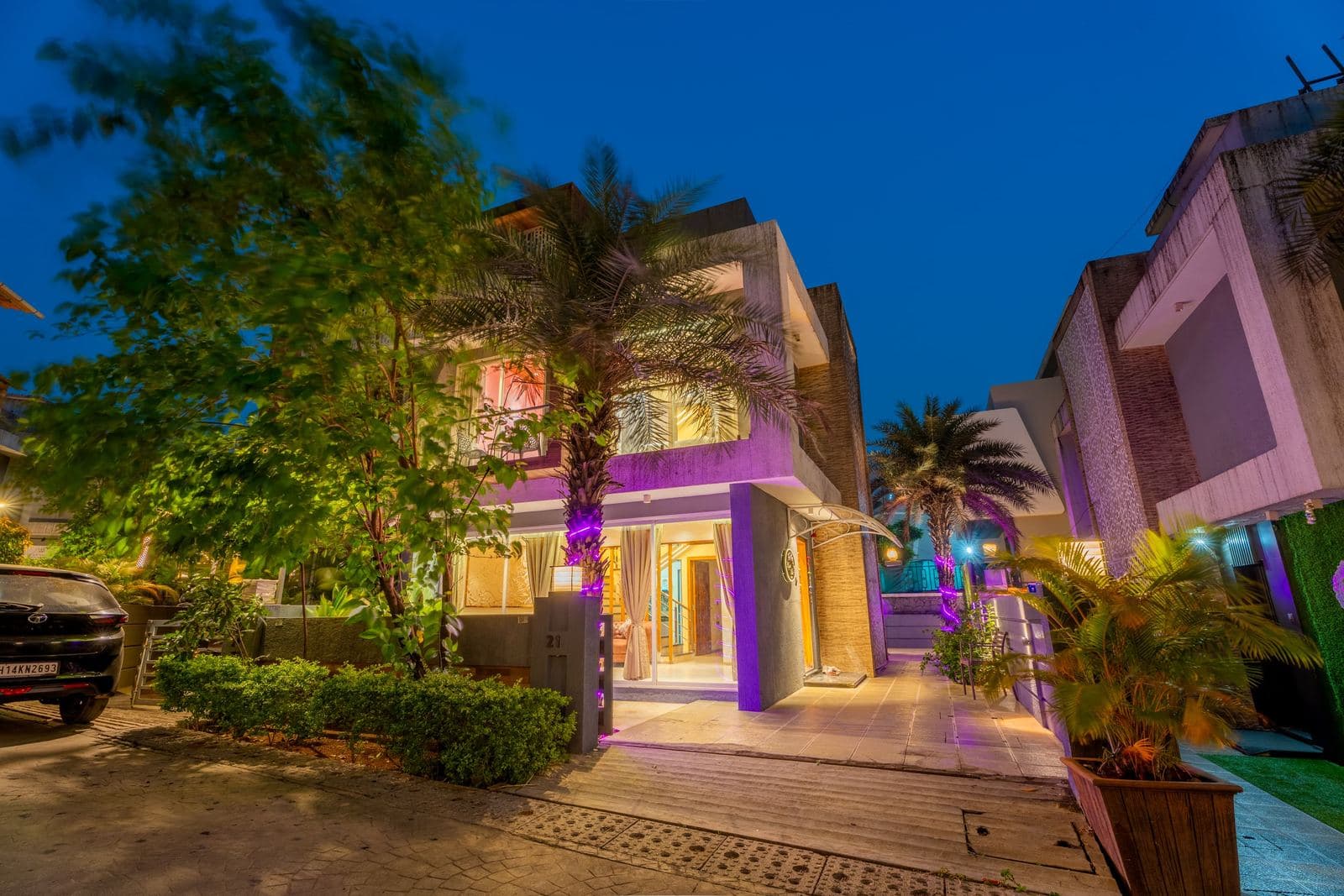 Villa exterior at dusk with palm trees and accent lighting