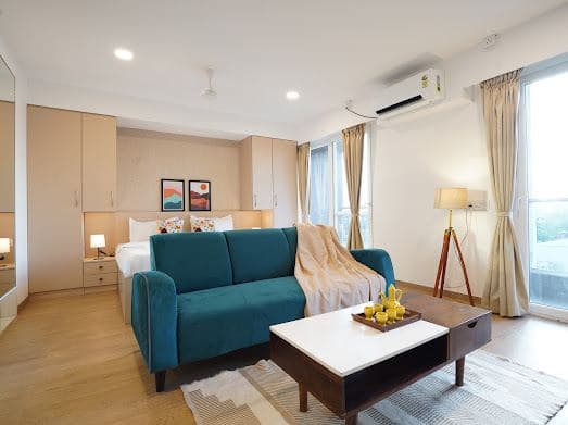 Living area with a teal sofa, wooden coffee table, and sliding glass doors to the balcony