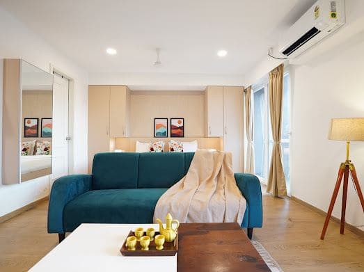 Lounge seating with a teal sofa, a tray of cups on the coffee table, and a full-length mirror nearby