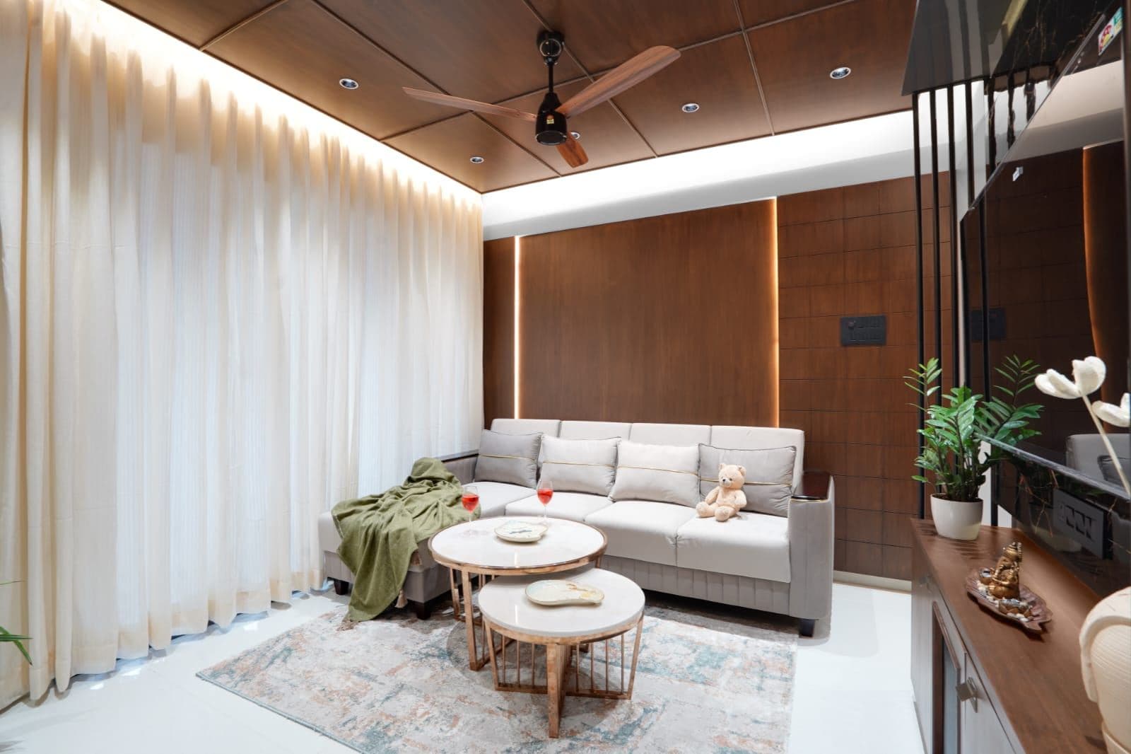 Sectional sofa with sheer curtains and nested marble-and-brass coffee tables