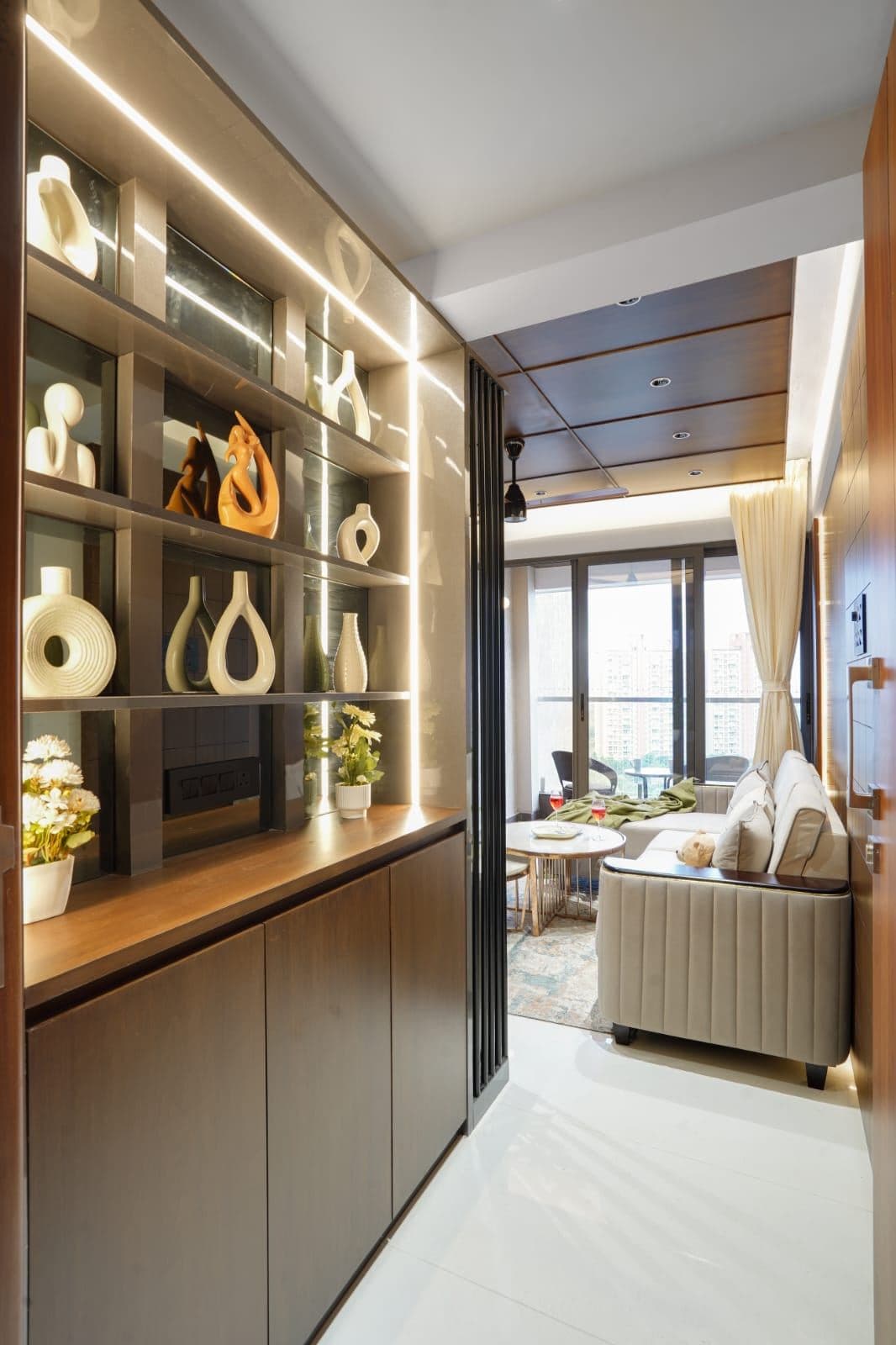Entry passage with a lit display shelf of decorative vases leading to the living room