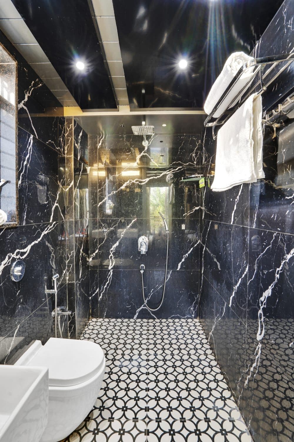 Black marble bathroom with rain shower and wall-mounted toilet