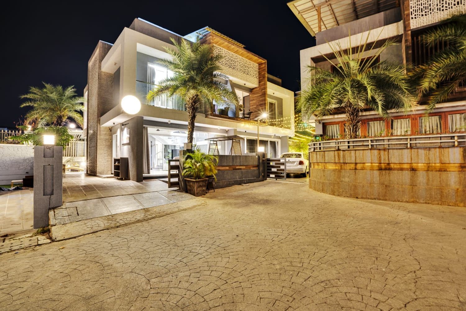 Villa exterior lit up at night with palm-lined driveway