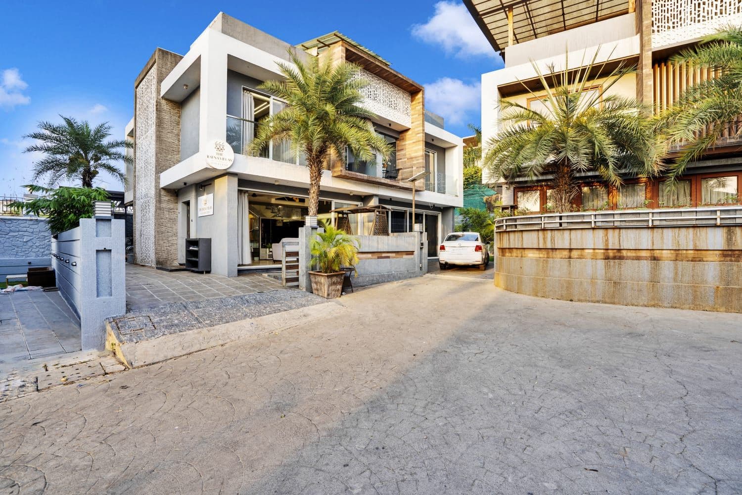 Villa exterior with palm trees and private driveway in daylight