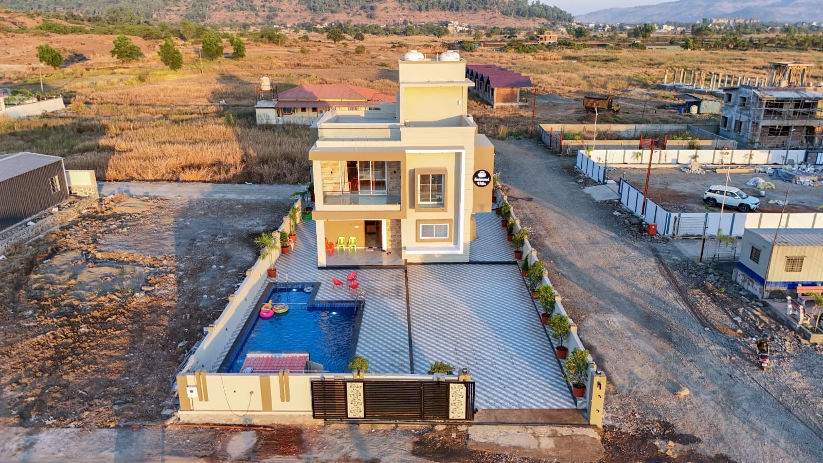 Aerial daytime view of the villa and rooftop pool deck surrounded by open land