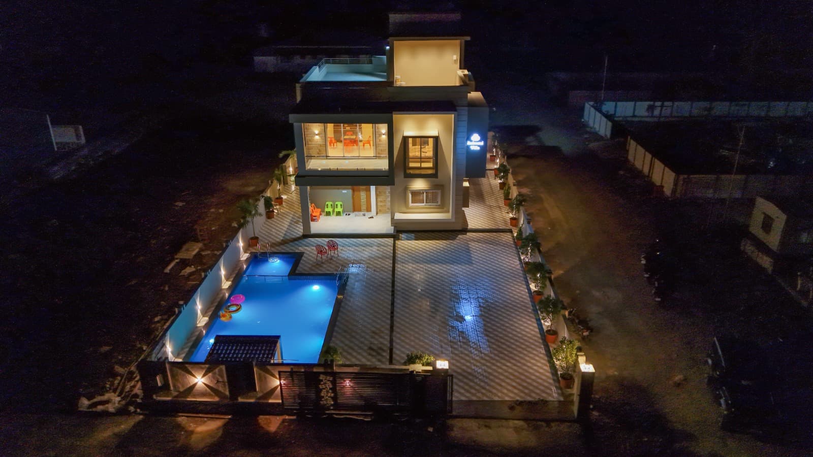 Aerial night view of the lit-up villa and rooftop pool