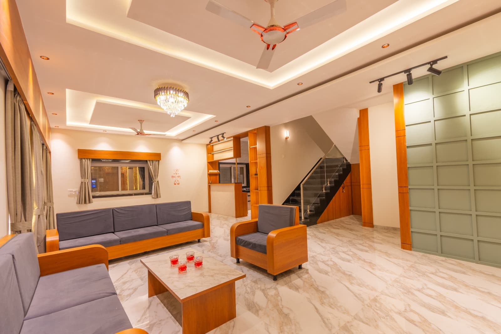 Living room with grey sofas and marble flooring beside the staircase