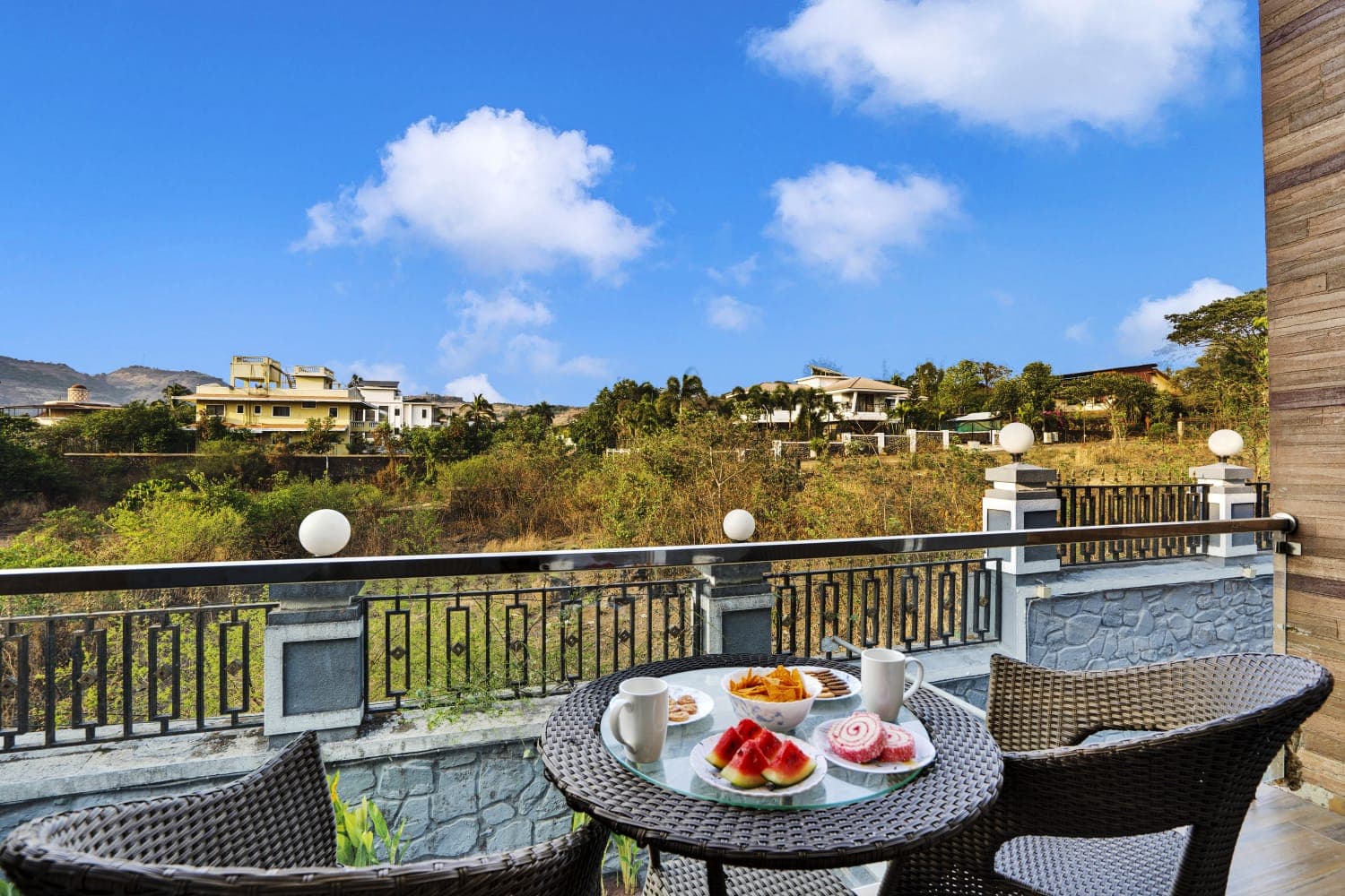 Balcony seating overlooking the green Lonavala hills under a blue sky
