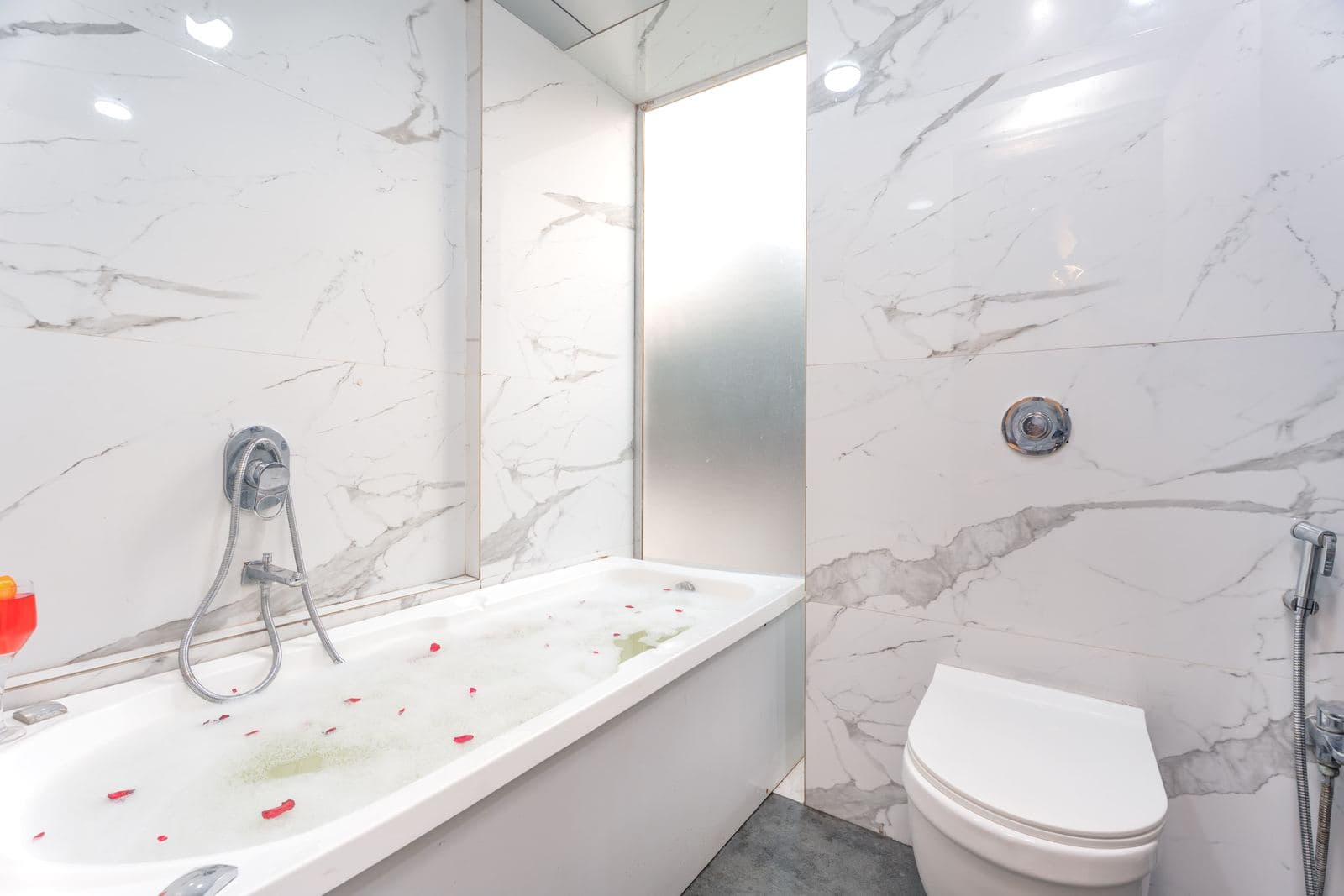 Bright marble bathroom with jacuzzi tub and rose petals