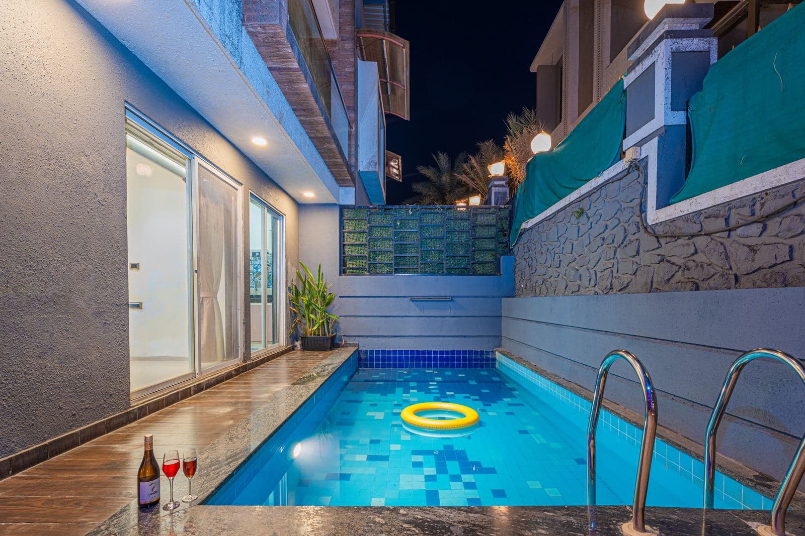 Plunge pool lit at night with a pool float and wine service