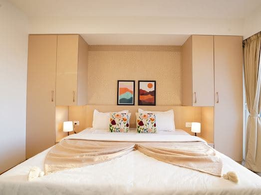 Bedroom with built-in wardrobes, bedside lighting, and framed sunset artwork above the headboard
