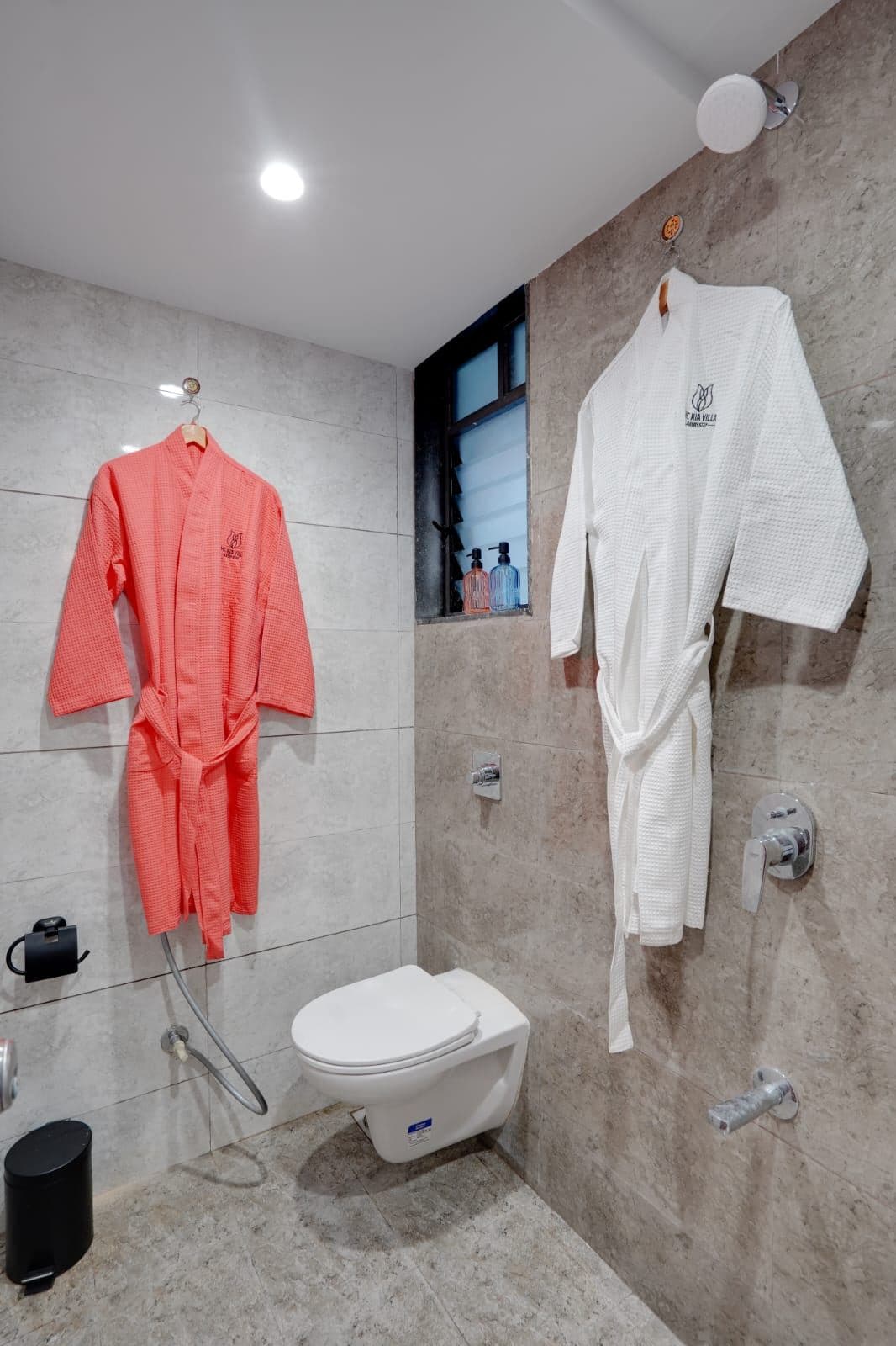 Bathroom with wall-hung toilet, shower, and robes hanging by the window