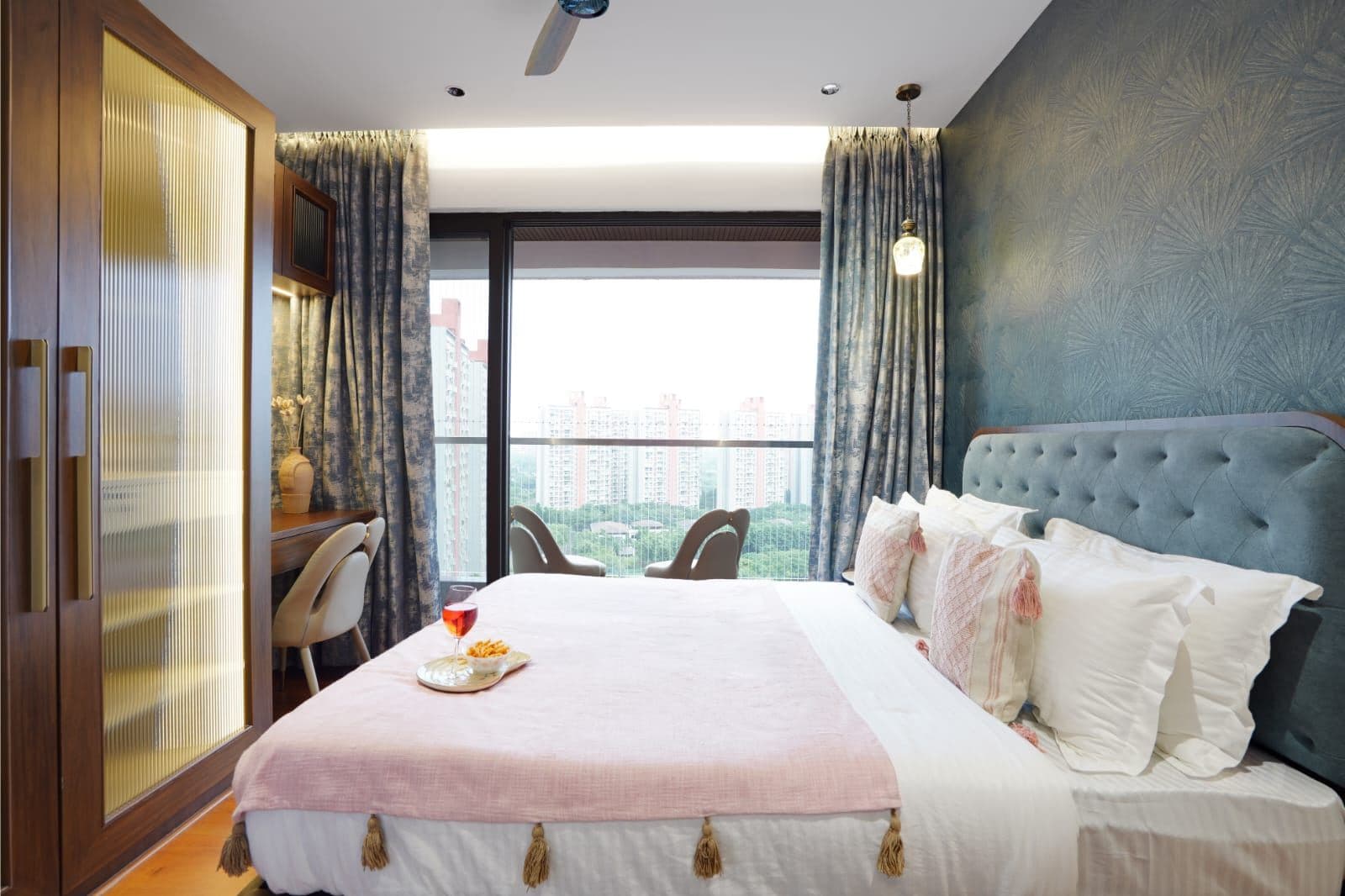 Bedroom with tufted headboard, fluted-glass wardrobe and a balcony view of the skyline