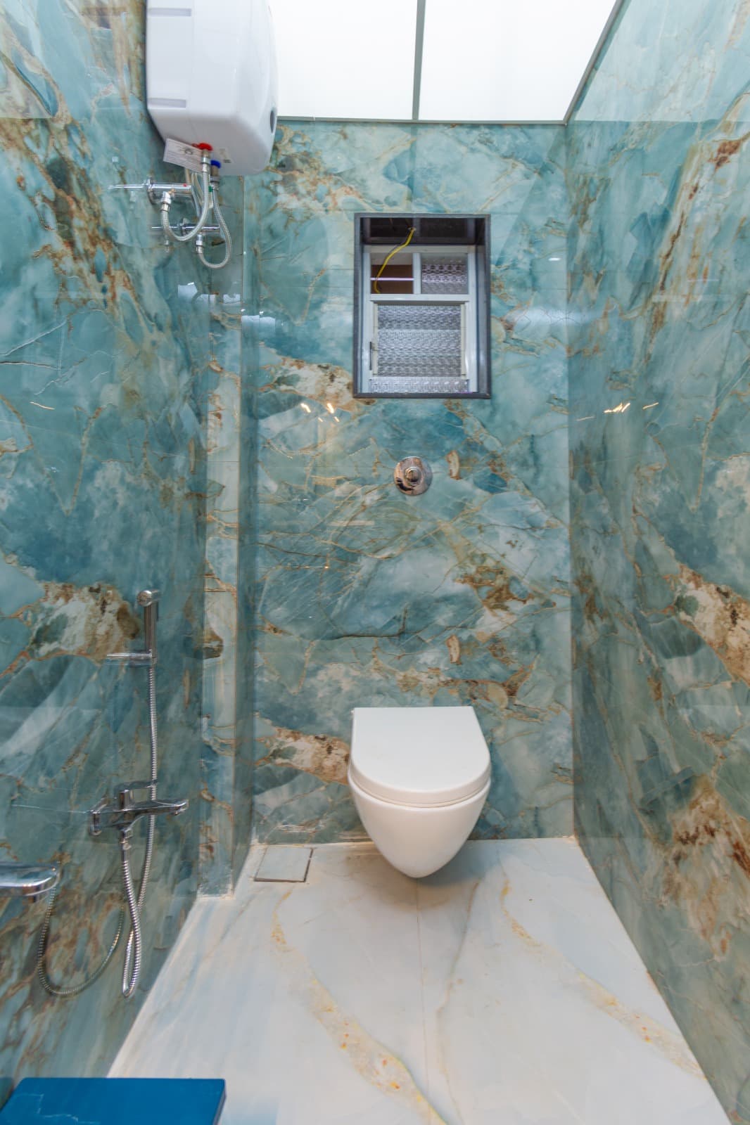 Teal marble bathroom with rain shower and wall-mounted toilet