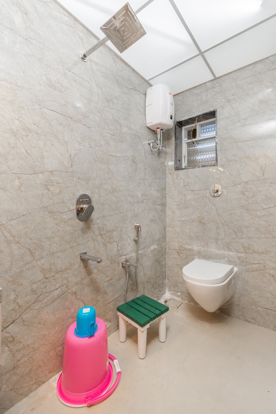 Beige marble bathroom with rain shower and wall-mounted toilet
