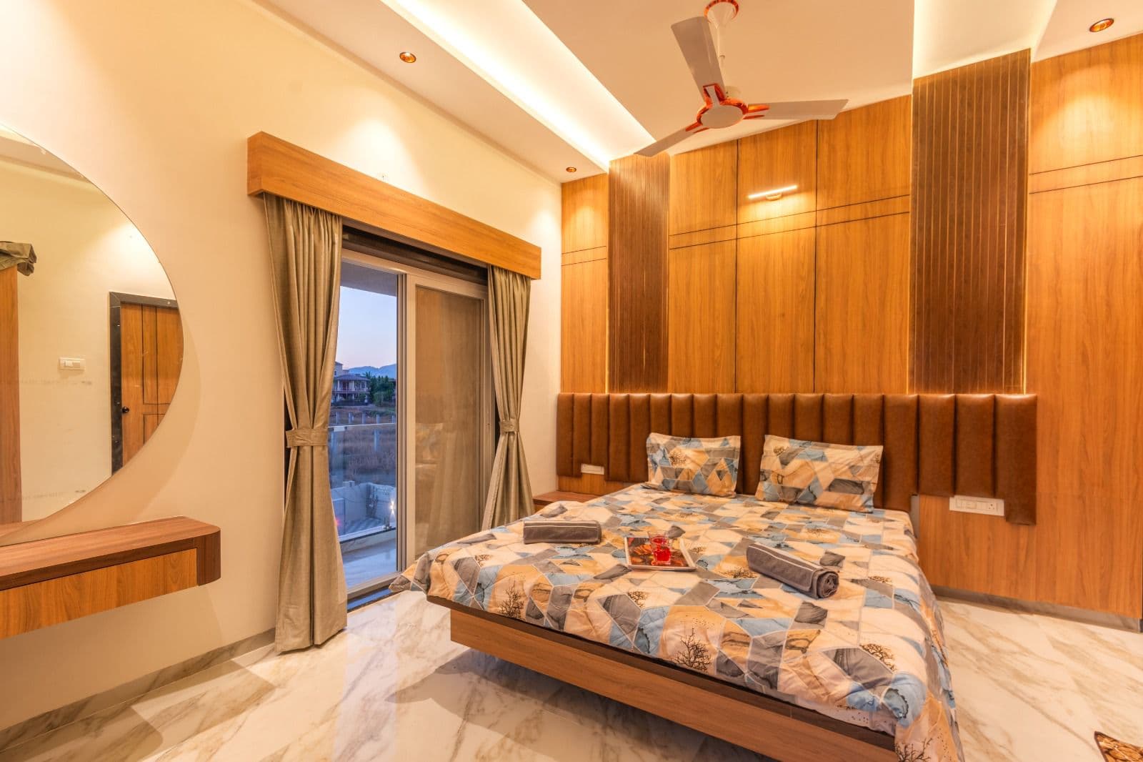 Bedroom with wood-panelled headboard wall opening to a balcony view