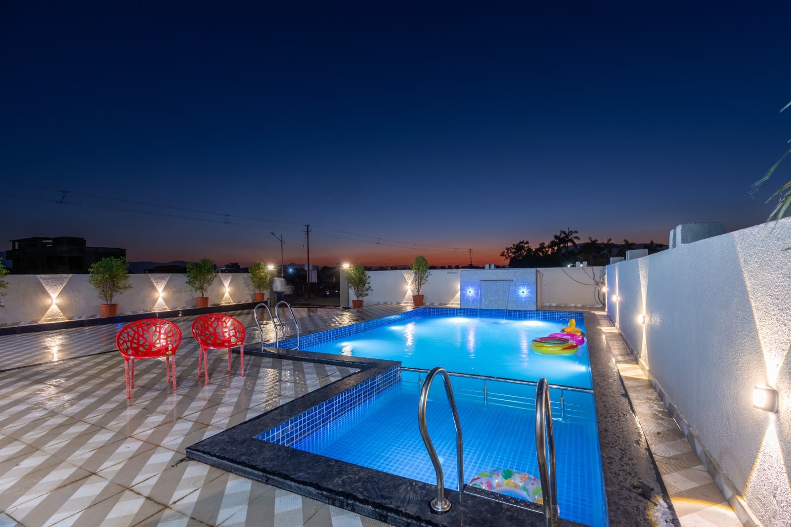 Rooftop pool with red chairs and pool floats at dusk