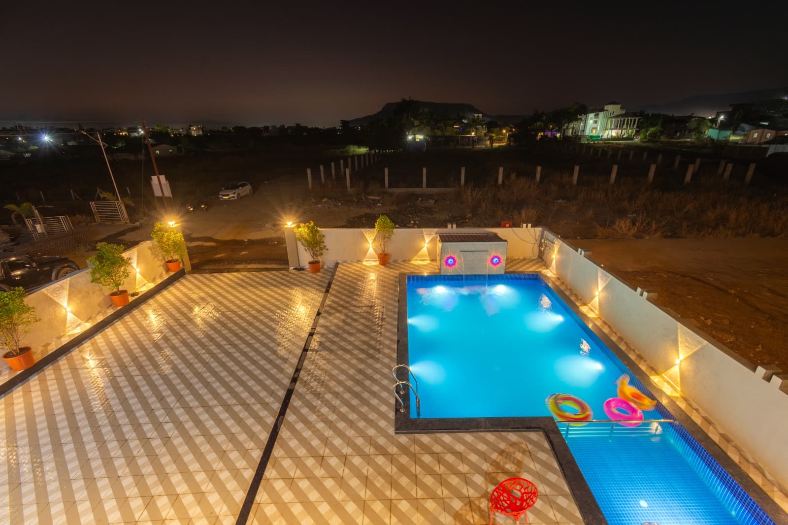 Rooftop pool deck with colourful water-jet fountain lit up at night